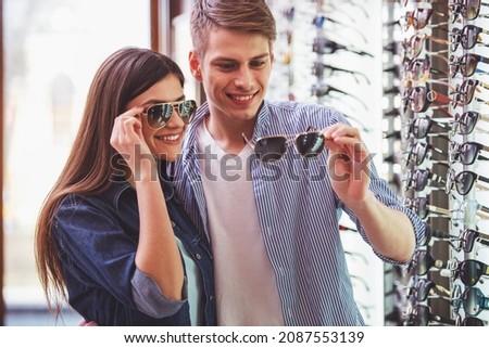 Young couple at optician in the store, they looking for glasses.