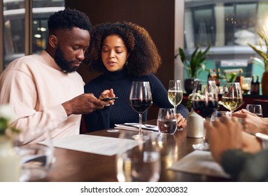 Young Couple Ordering On Phone In Wine Bar