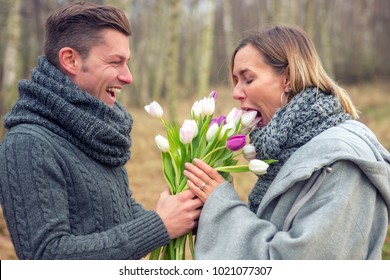 Young Couple Outdoors With Flowers Being Silly And Happy