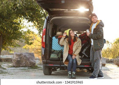 Young Couple Packing Camping Equipment Into Car Trunk Outdoors