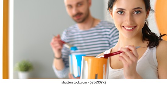 Young Couple Painting Wall At Home