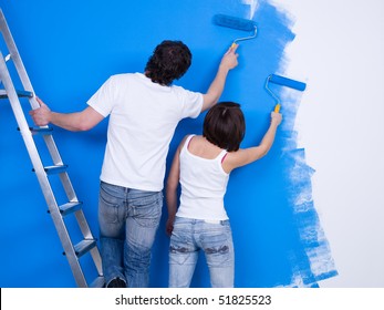 Young Couple Painting The Wall With Roller Together