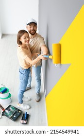 Young Couple Painting Wall In Room