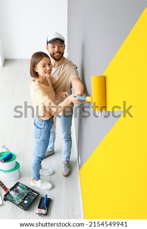Young couple painting wall in room