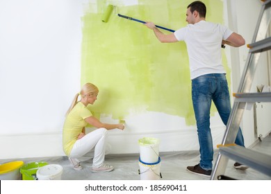 Young Couple Painting Wall In Their Room