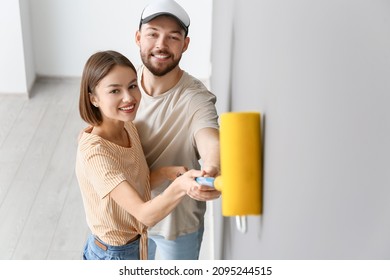 Young Couple Painting Wall In Their New House