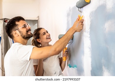 Young Couple Painting Wall In Their Home.