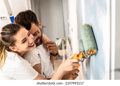 Young Couple Painting Wall In Their Home.