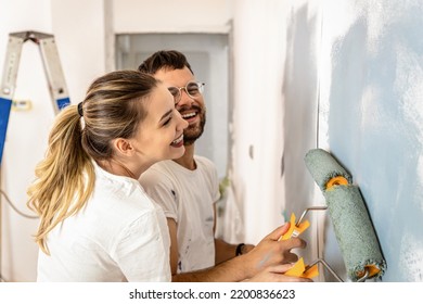 Young Couple Painting Wall In Their Home.