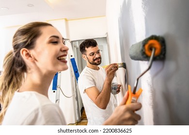 Young Couple Painting Wall In Their Home.