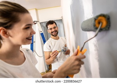 Young Couple Painting Wall In Their Home.