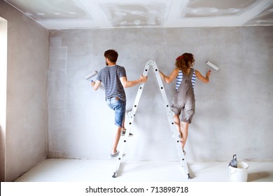 Young Couple Painting Walls In Their New House.