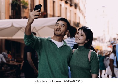 Young couple pausing in crowd for quick selfie, capturing candid photo with soft smiles and close connection, perfect for travel diary or personal video call snapshot