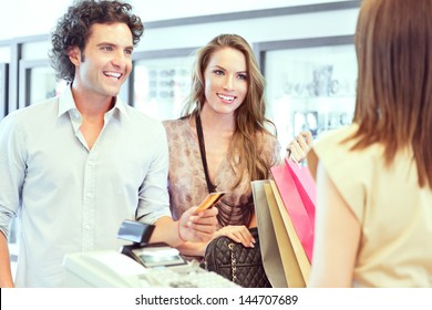 A young couple paying for the clothes they have just bought. - Powered by Shutterstock