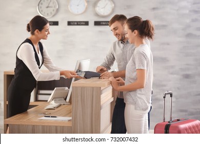 Young couple paying for hotel room at reception