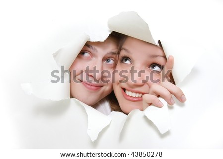 young couple peeping through hole in white paper