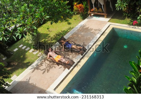 young couple of people relax on villa by swimming pool
