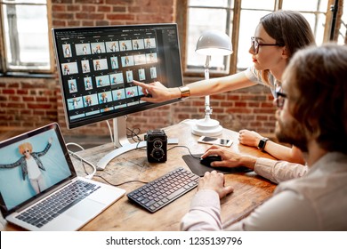 Young couple of photographers working with woman's portraits at the working place with two computers in the studio - Powered by Shutterstock