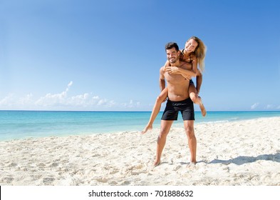 Young couple piggyback ride at  the beach