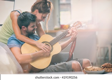 Young couple playing guitar on couch indoor - Powered by Shutterstock