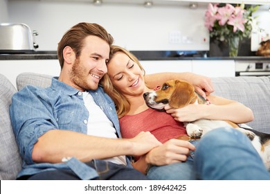 Young Couple Playing With Pet Dog At Home