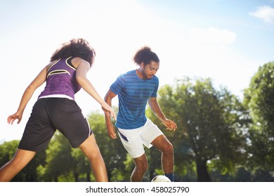 Young couple playing soccer in park - Powered by Shutterstock