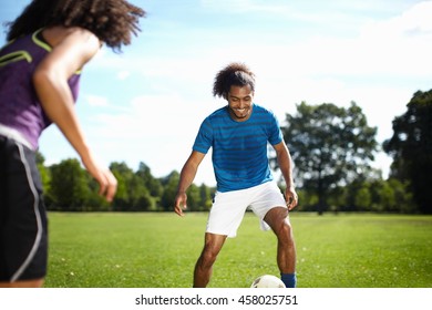 Young couple playing soccer together in park - Powered by Shutterstock