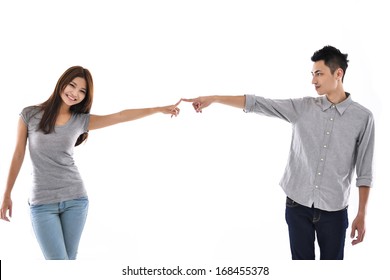 Young Couple Pointing At Each Other Against A White