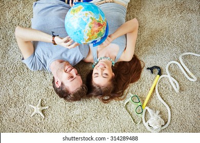 Young Couple Pointing At Globe While Dreaming Of Summer Vacations