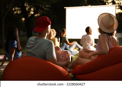 Young couple with popcorn watching movie in open air cinema. Space for text