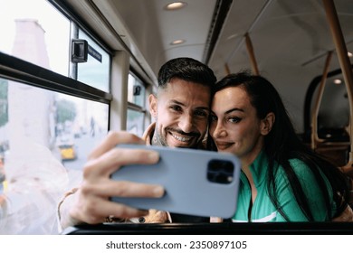 A young couple pose for a fun selfie together aboard a bus. - Powered by Shutterstock