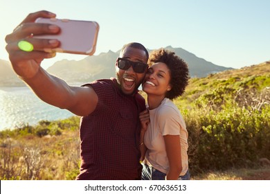 Young Couple Pose For Holiday Selfie On Clifftop