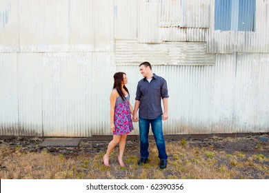 A Young Couple Poses For Some Engagement Photos In Urban Outdoor Settings.