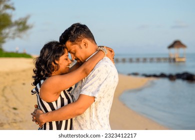 Young couple posing for photograph on a sea beach. Hut can be seen in the background with bokeh effect  - Powered by Shutterstock