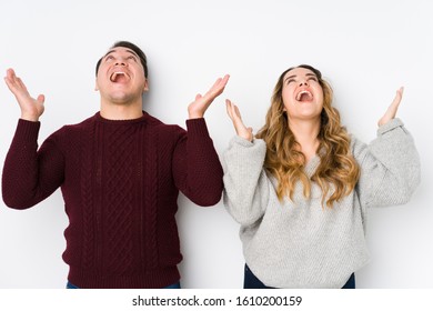 Young couple posing in a white background screaming to the sky, looking up, frustrated.
