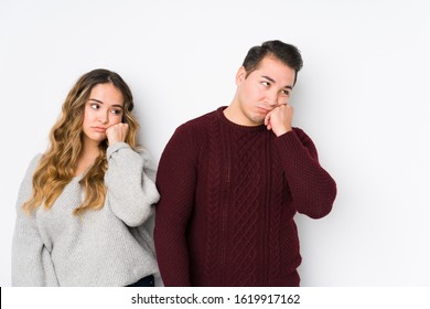 Young couple posing in a white background who feels sad and pensive, looking at copy space.