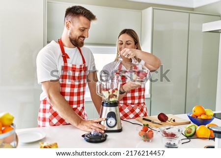 Young couple pouring water making smoothie cooking at kitchen