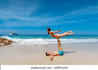 Young couple practice acro yoga on the beach over sea and big yacht background. - Powered by Shutterstock