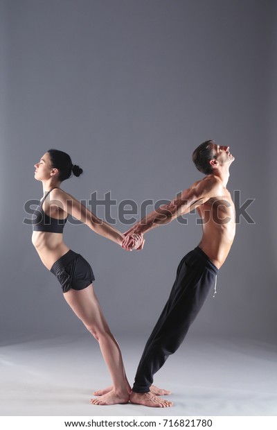 Young couple practicing acro\
yoga on mat in studio together. Acroyoga. Couple yoga. Partner\
yoga.