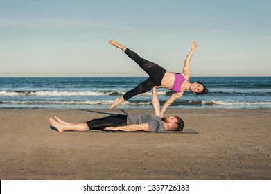 Young couple practicing acroyoga exercises in the evening on the beach over sea background - side star 