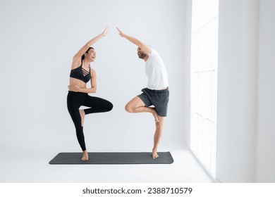 Young couple practicing yoga in a white room of studio. - Powered by Shutterstock