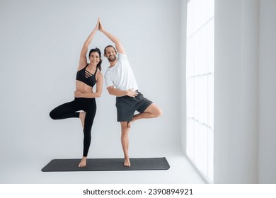 Young couple practicing yoga in a white room of studio. - Powered by Shutterstock