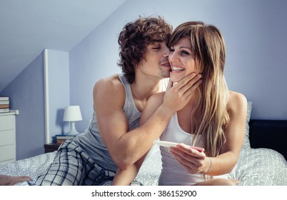 Young Couple With Pregnancy Test In Bedroom