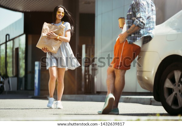 Young couple preparing for vacation trip on the
car in sunny day. Woman and man shopping and ready for going to
sea, riverside or ocean. Concept of relationship, vacation, summer,
holiday, weekend.