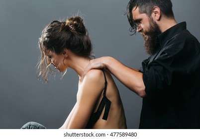 Young Couple Of Pretty Sexy Woman In Black Jeans And Bra Has Slim Body And Handsome Bearded Man With Long Beard In Shirt Doing Massage On Grey Background