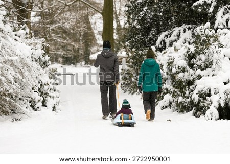 Young couple pulling a small child on a sled through the winter landscape.