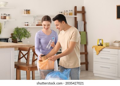 Young couple putting garbage in trash bin at home - Powered by Shutterstock