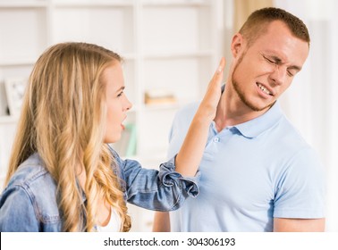 Young couple quarreling at home. Woman giving slap to her husband.