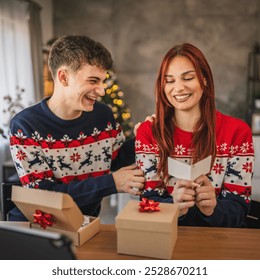 Young couple read greeting card from christmas gift via video call on digital tablet at home - Powered by Shutterstock