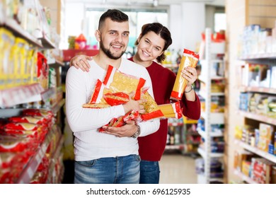 Young Couple Reading Lable Of Pasta At Supermarket